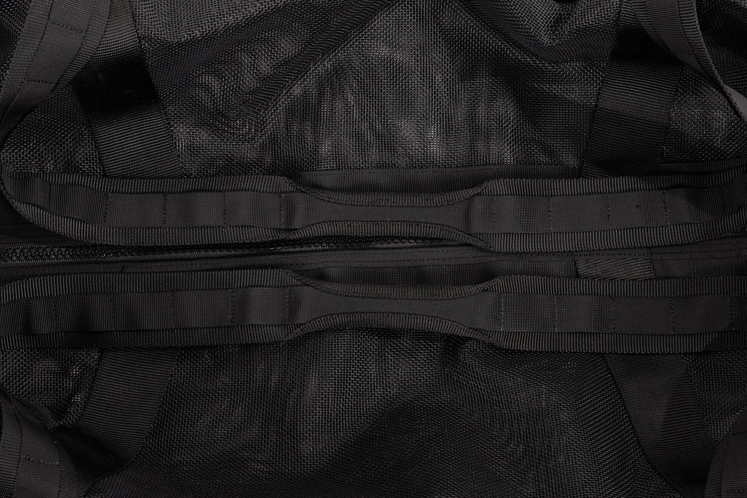 Close-up of a black gear bag showing mesh fabric, woven webbing straps, and a central zipper pocket detail.