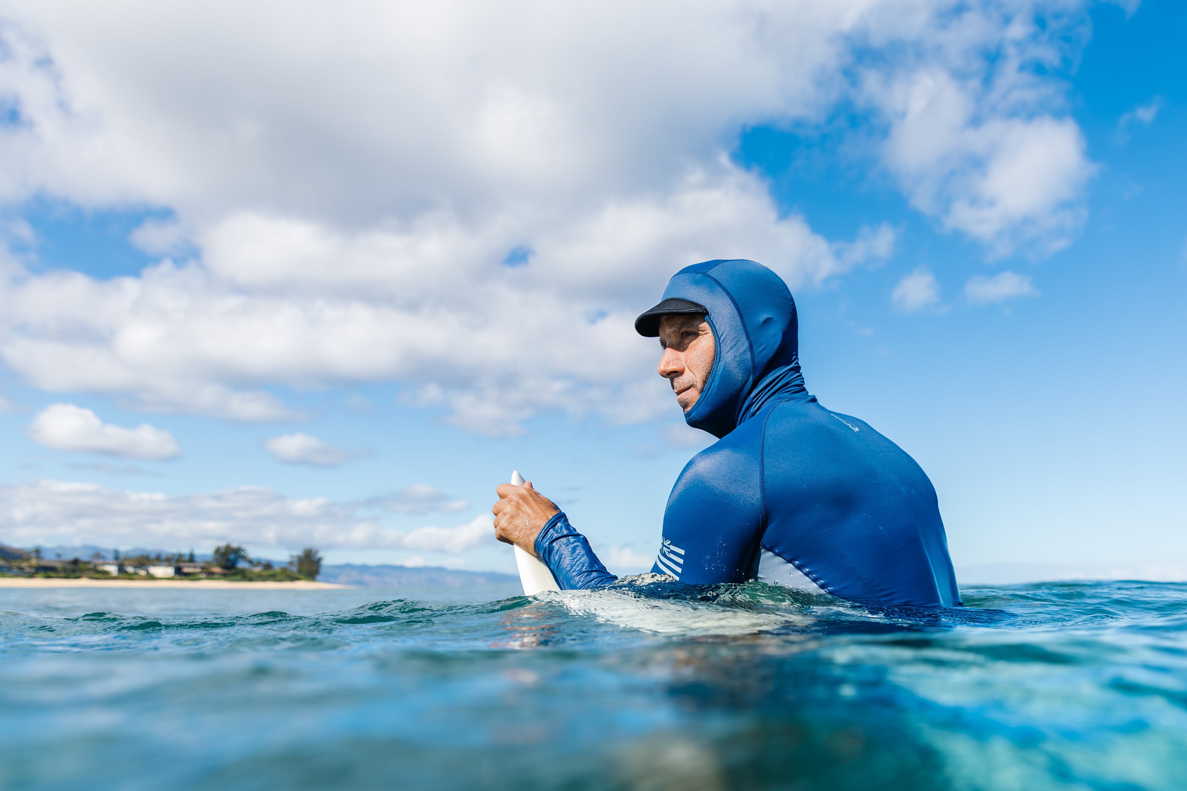 Person wearing a blue wetsuit in the ocean with a clear sky.