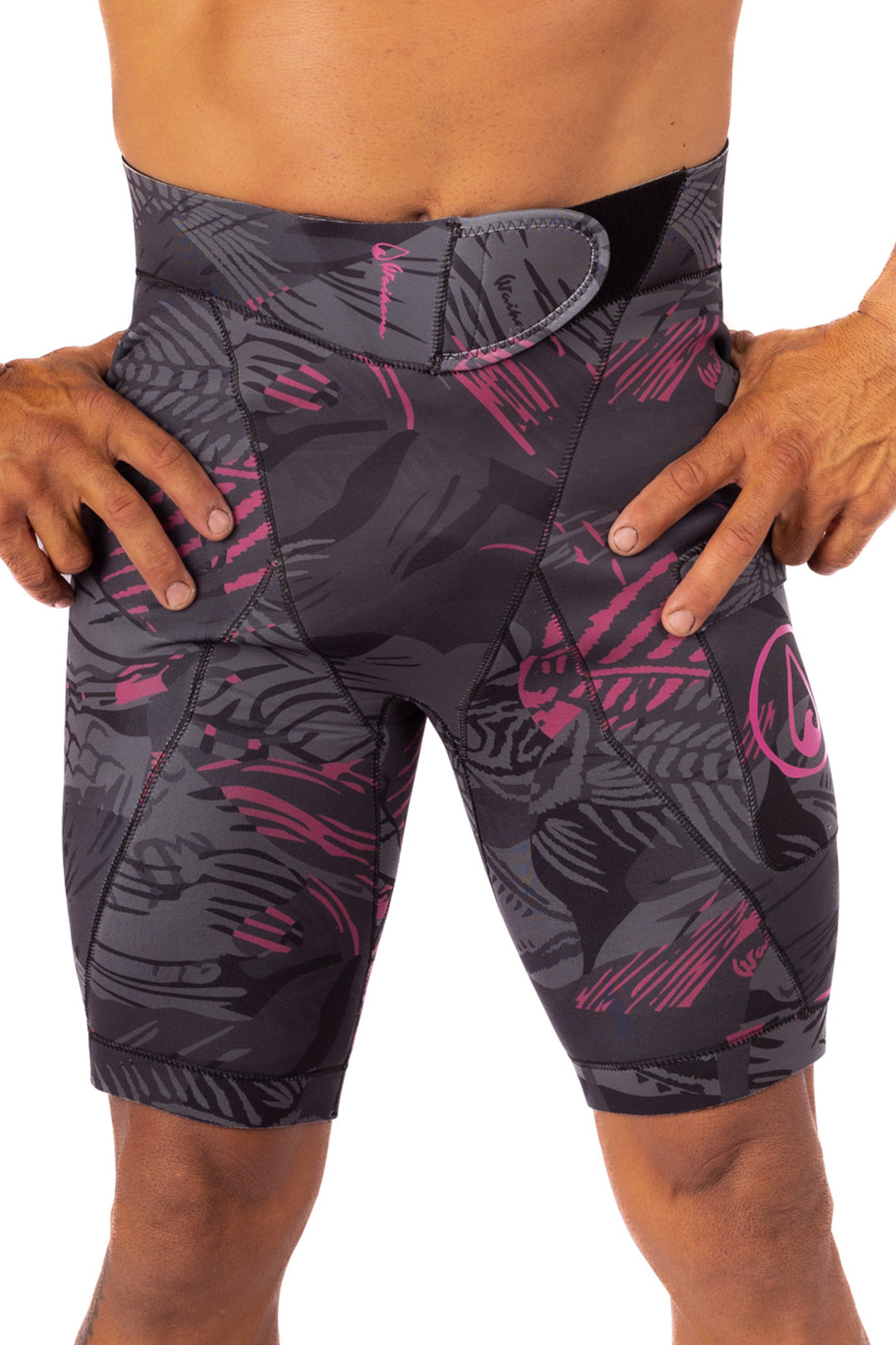 Male model wearing Waihana Pink Fishbone Tech Jammers wetsuit shorts in a dark grey and pink fishbone camo pattern, shown from the waist down against a white studio background.